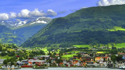 Norwegisches Dorf liegt idyllisch am Fjord unter grünen Bergen.