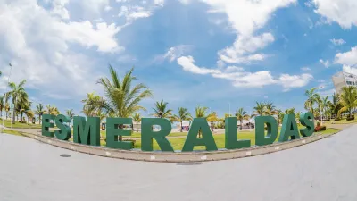 Der Schriftzug "ESMERALDAS" steht vor blauem Himmel und Palmen.