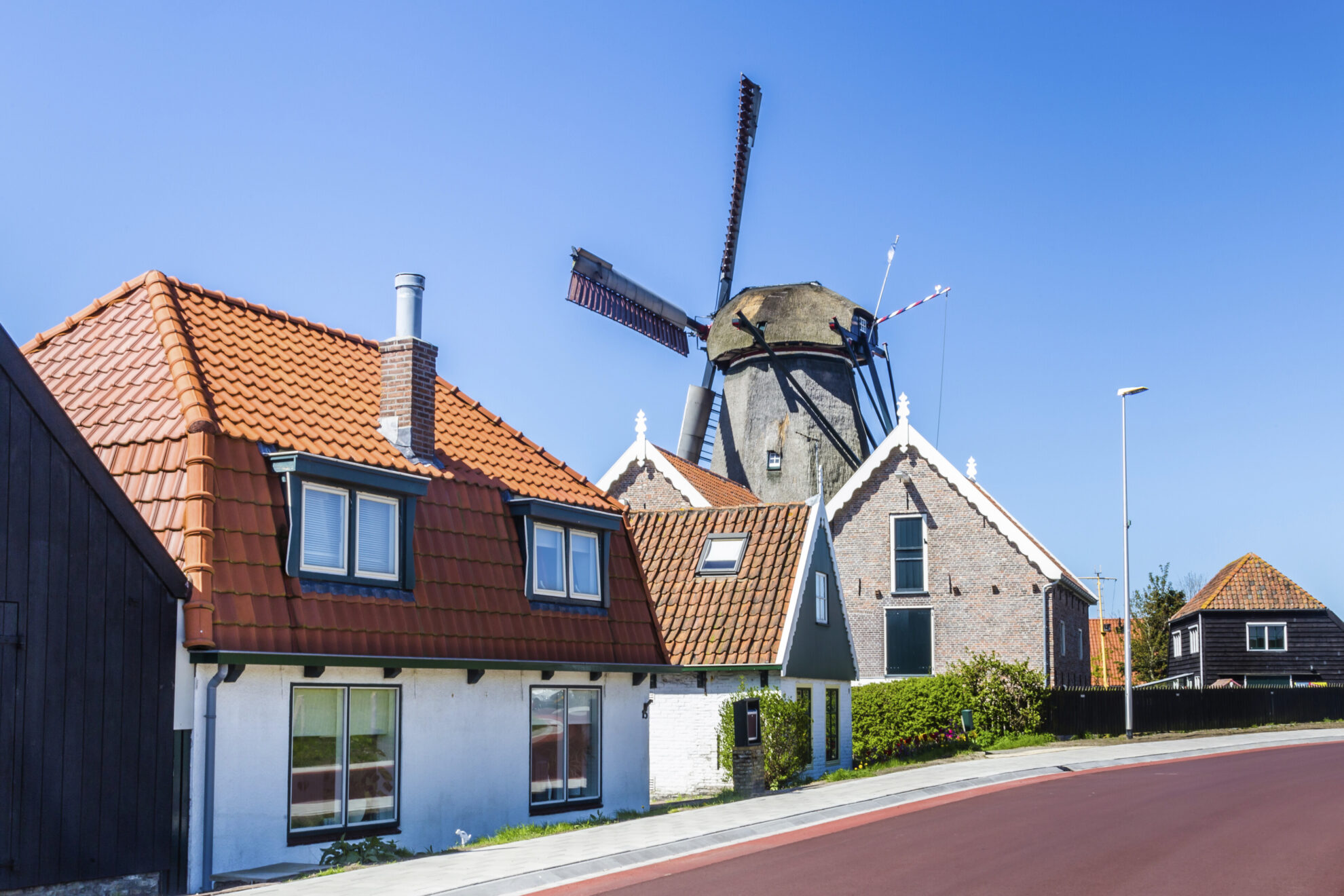 Häuserreihe vor einer Windmühle in Oudeschild, Niederlande